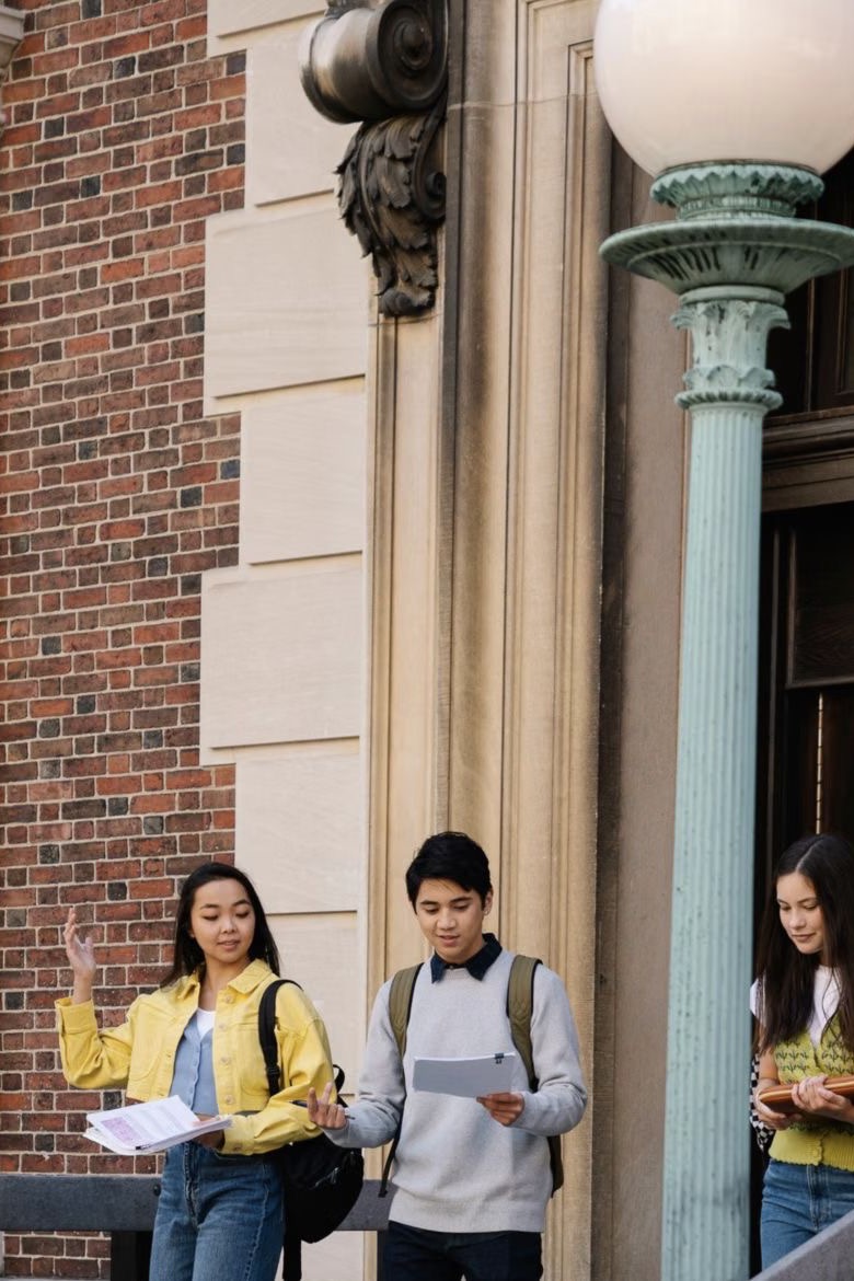 Group of university students walking together with study materials on campus